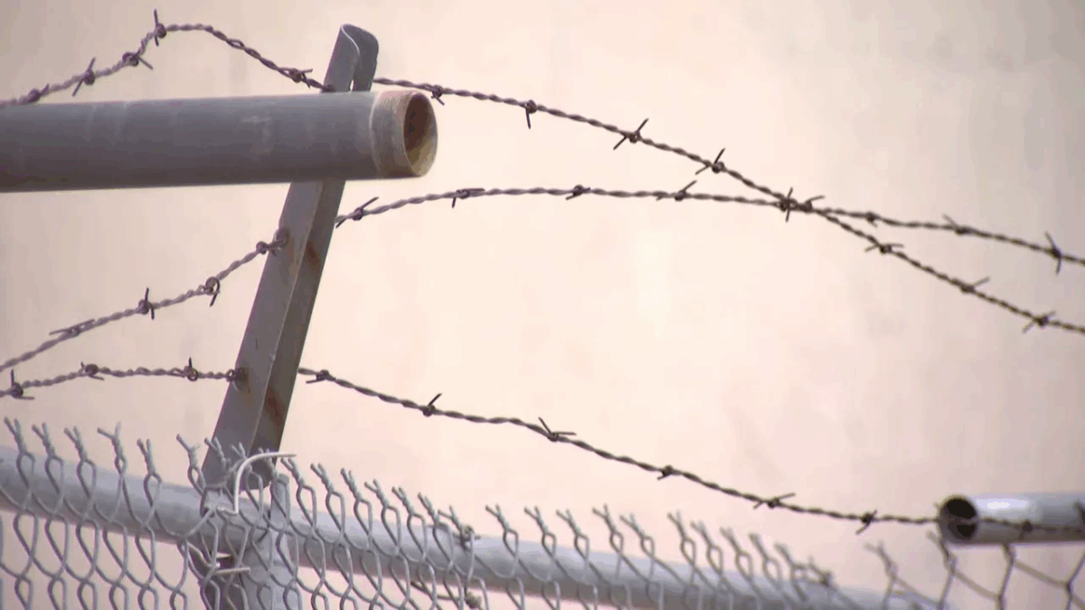 Close-up of barbed wire and chain-link fence around an abandoned industrial site