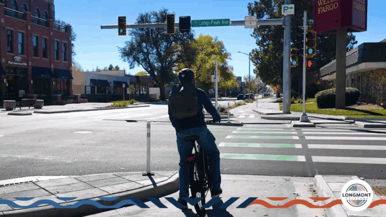 Cyclist waiting at the corner island holding area facing the intersection ready to make a two-stage left turn