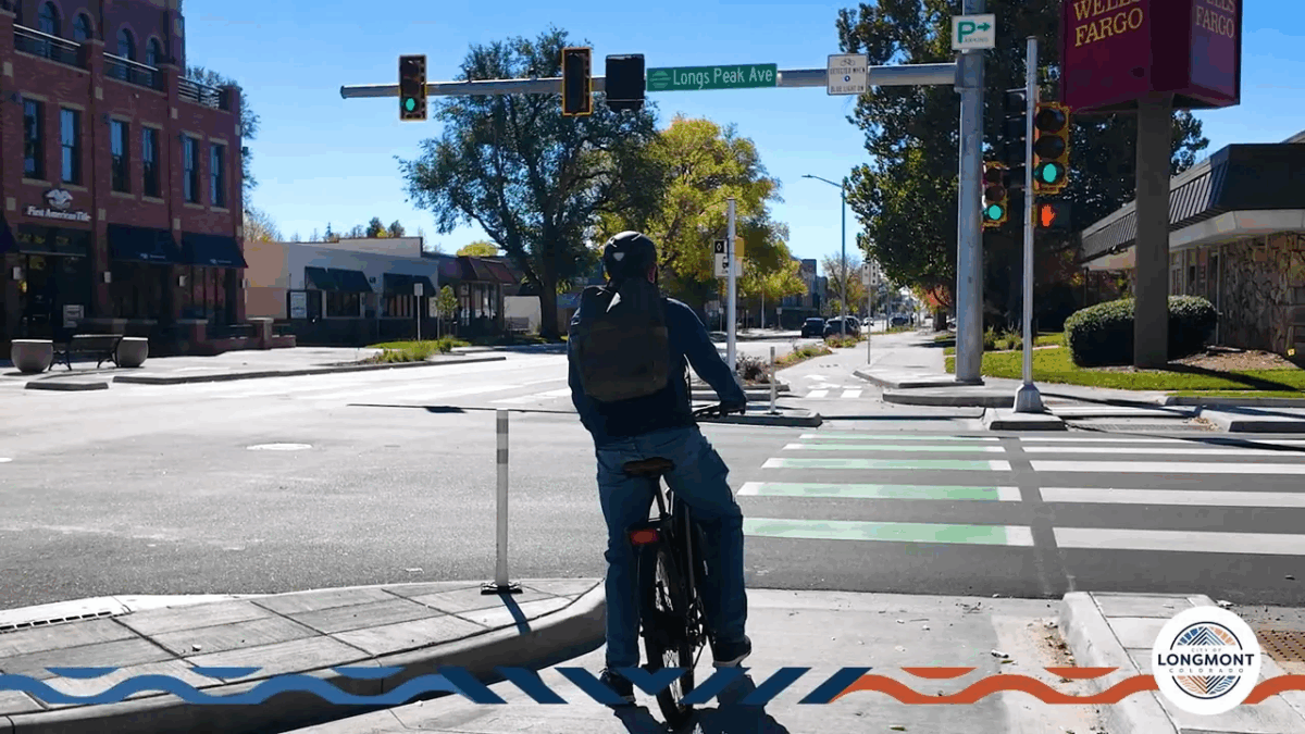 Cyclist waiting at the corner island holding area facing the intersection ready to make a two-stage left turn