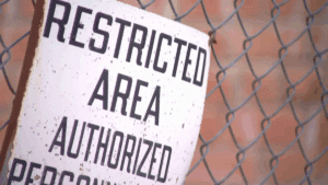 Restricted area sign on a chain-link fence at the abandoned sugar mill