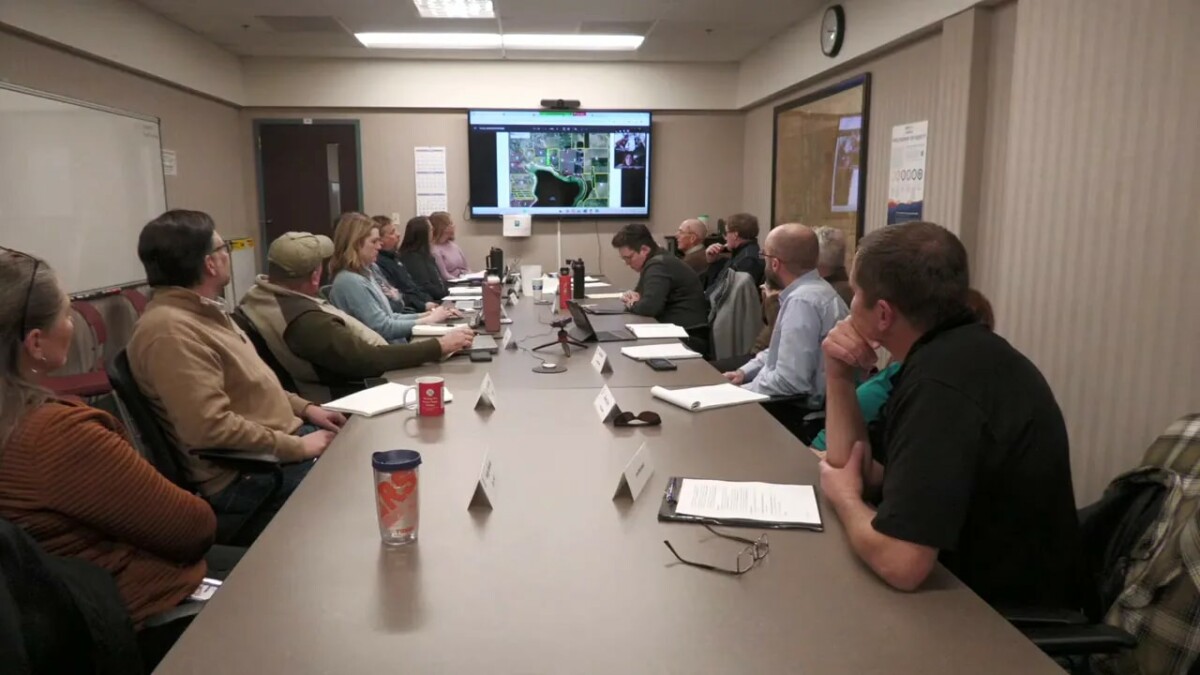 Wide view of a water advisory board meeting with attendees looking at a screen displaying a reservoir and parcel map