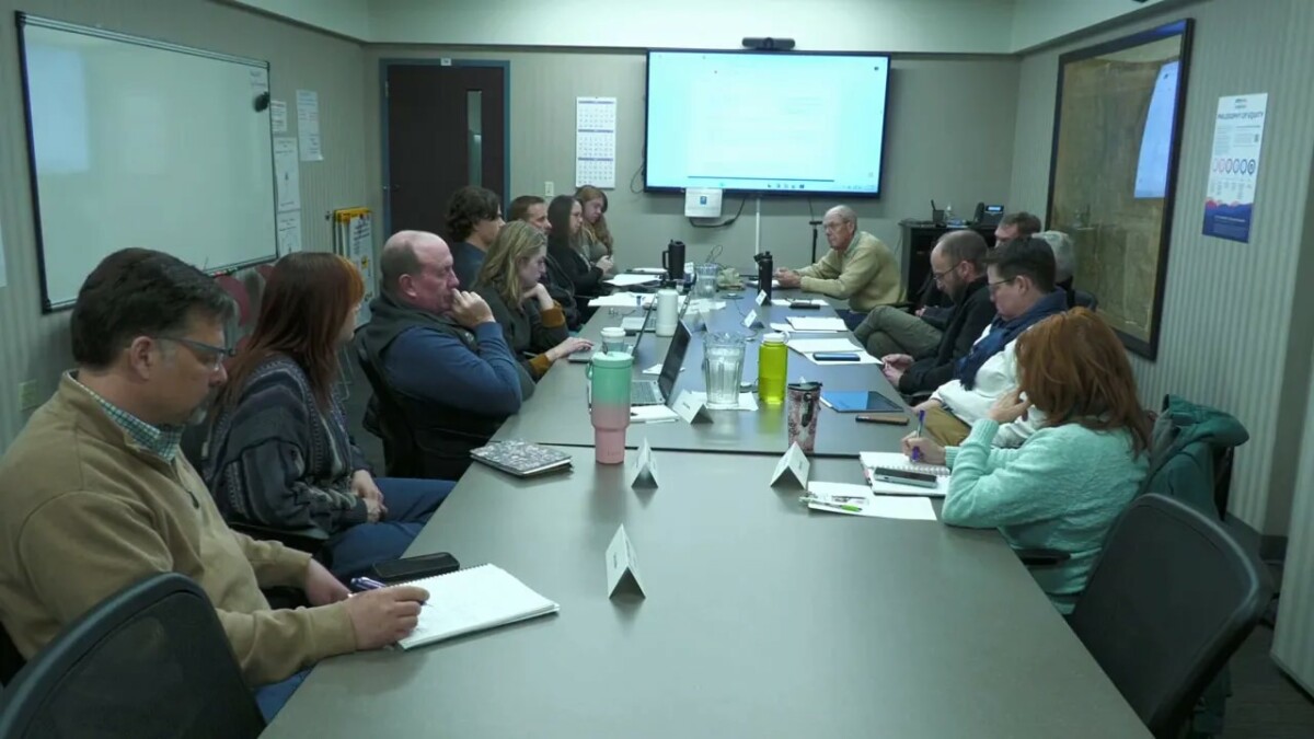 Longmont Water Board meeting attendees reviewing materials around a conference table with a projected slide