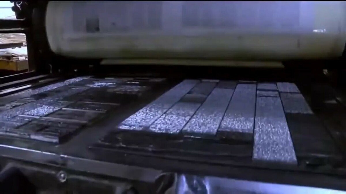 Printing press rollers moving over newspaper pages during production